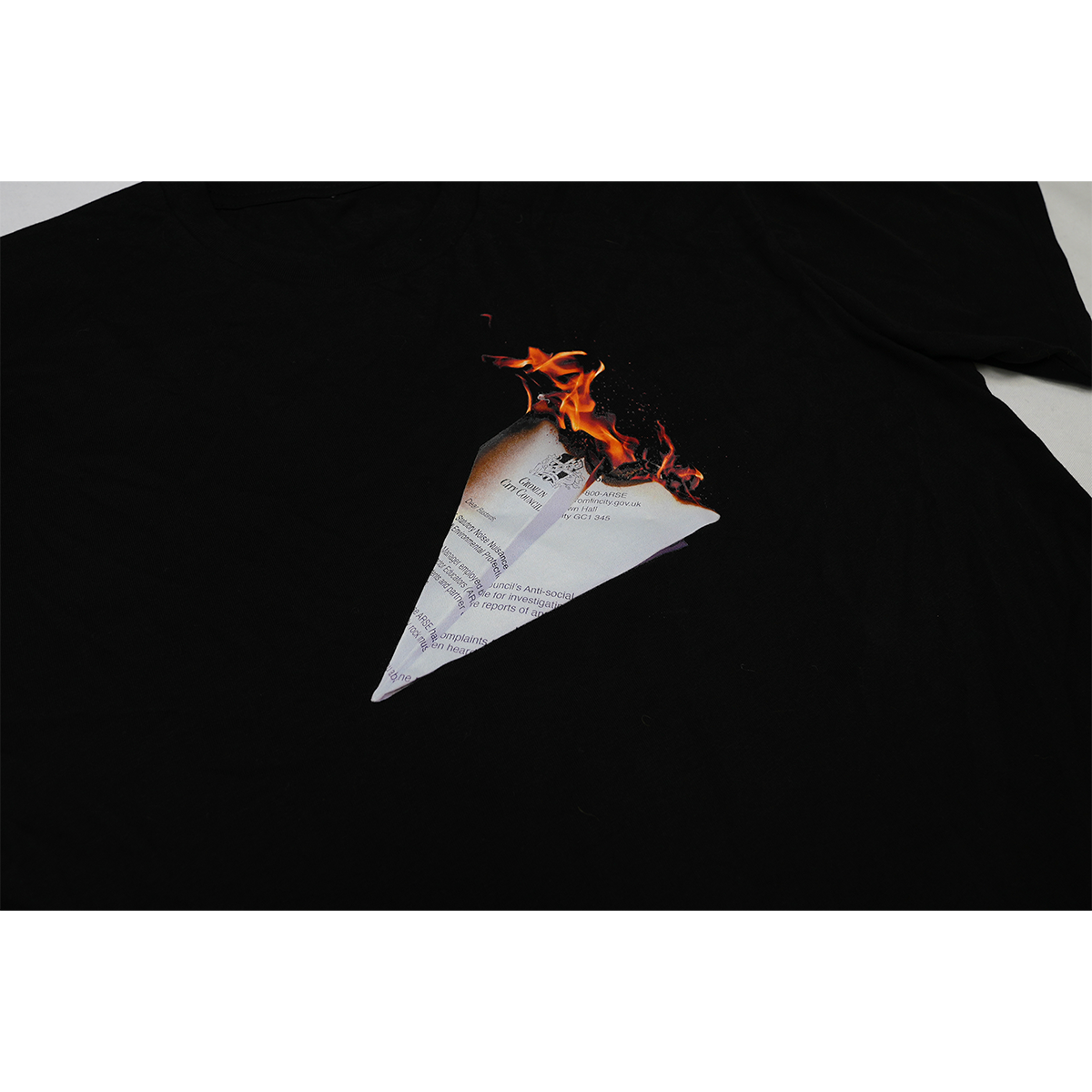 Detailed front view of a black unisex regular fit T-shirt featuring a burning paper plane graphic printed across the chest.