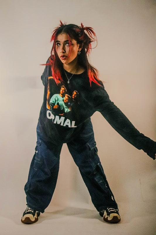 Person wearing a regular fit long-sleeve black tie-dye T-shirt featuring a photo image of Lovejoy with white capitalised text “NORMAL” printed underneath.