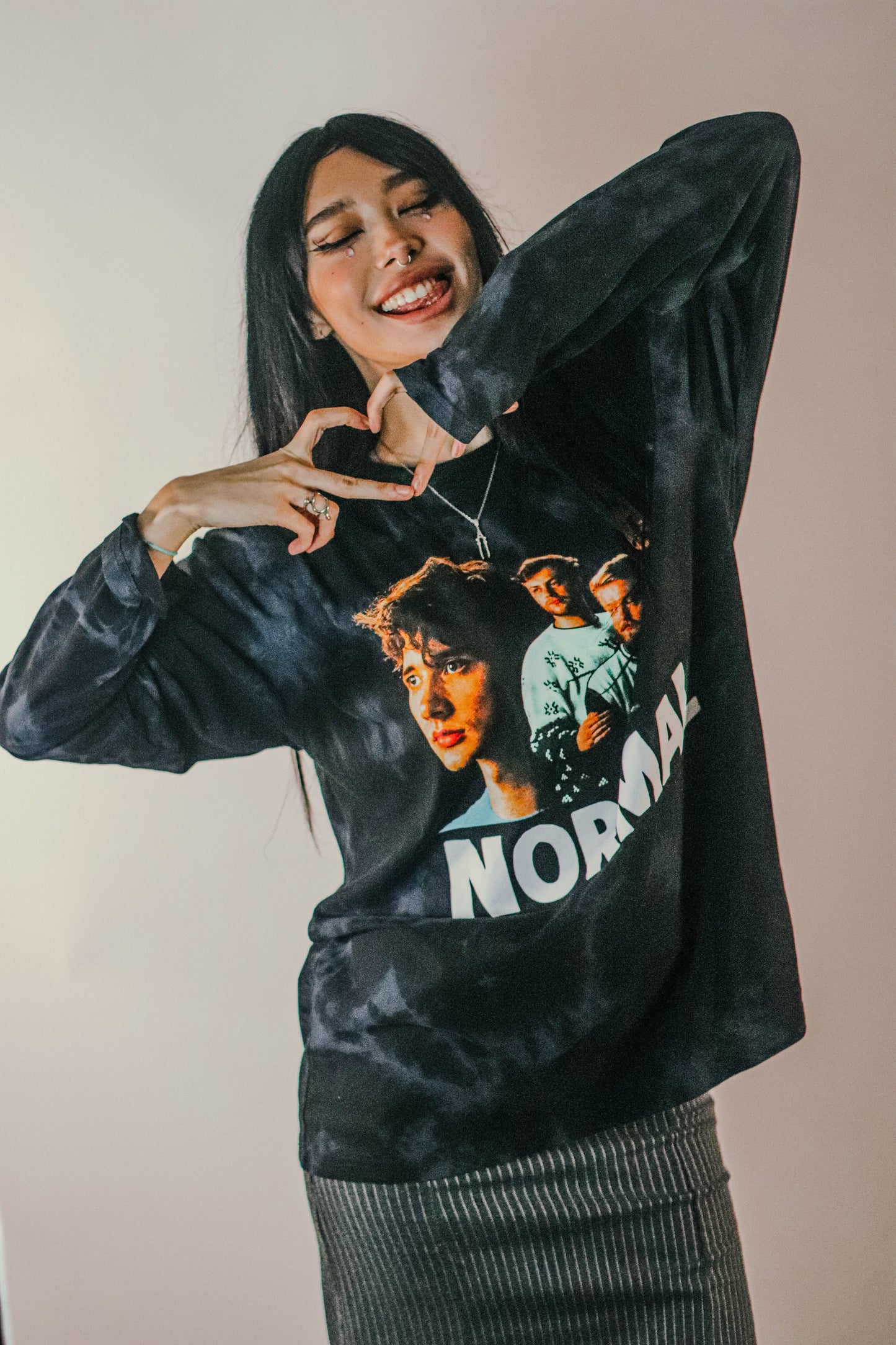 Person wearing a regular fit long-sleeve black tie-dye T-shirt featuring a photo image of Lovejoy with white capitalised text “NORMAL” printed underneath.